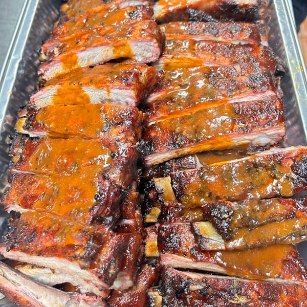 Close-up of Luka's Barbecue & Steakhouse's juicy, saucy BBQ ribs, cut into individual portions in a tray.